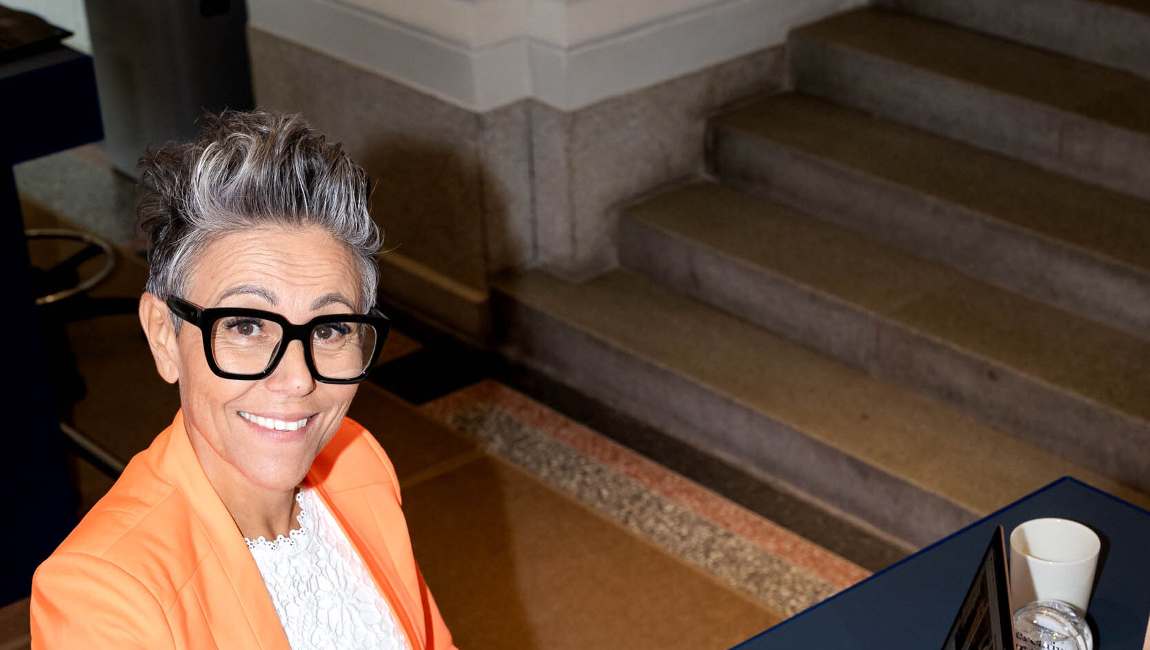 Kvinna i orange jacka arbetar inom kundtjänst.